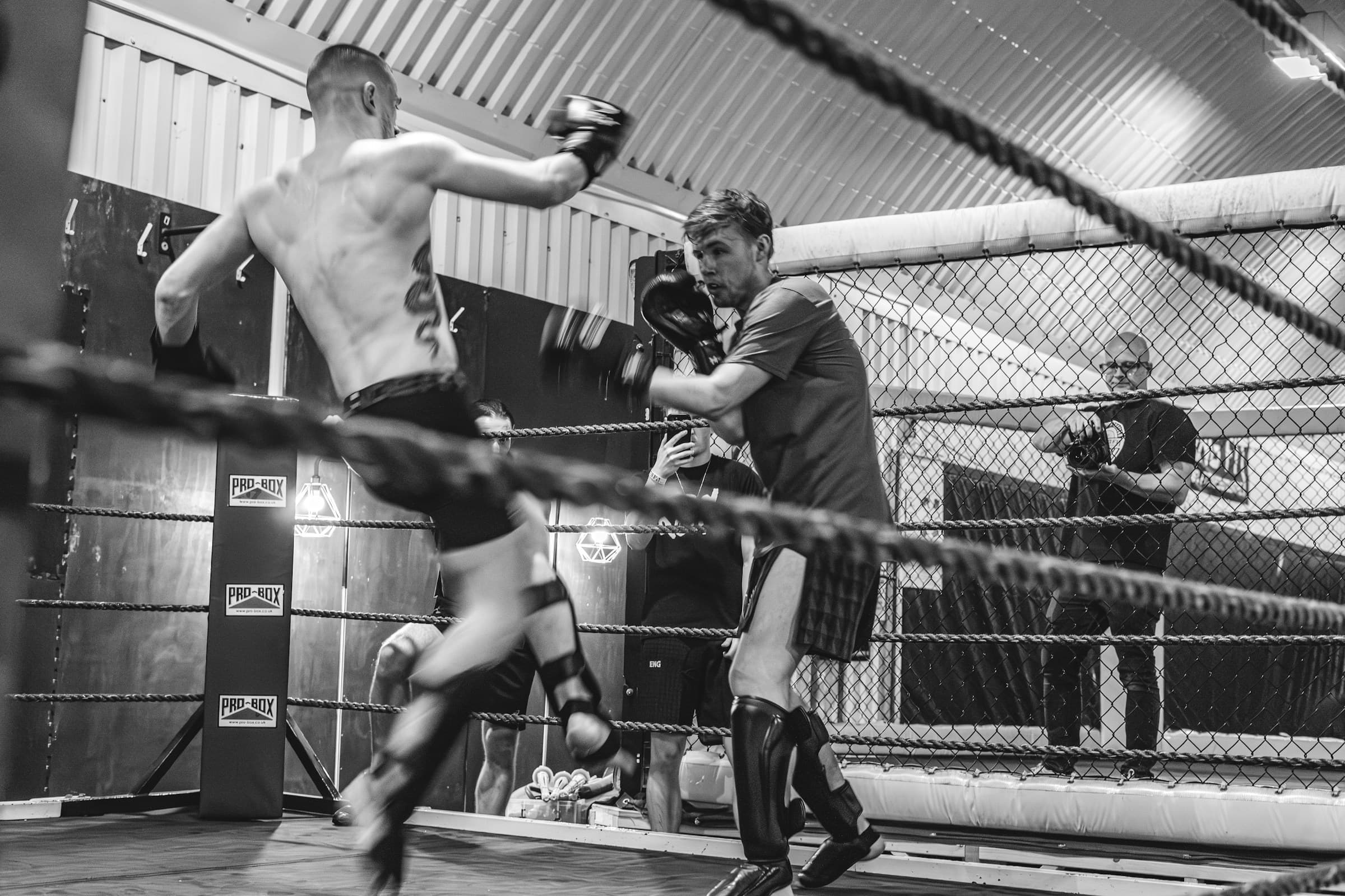 Un kickboxeur décoche un coup de pied vers les pattes d'ours de son coach, sur un ring